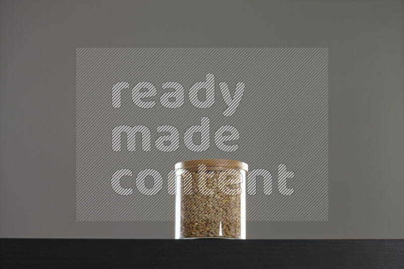 Hulled wheat in a glass jar on black background
