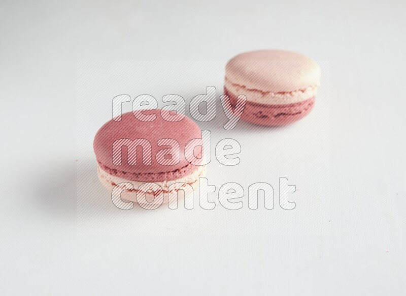 45º Shot of two Pink Litchi Raspberry macarons on white background