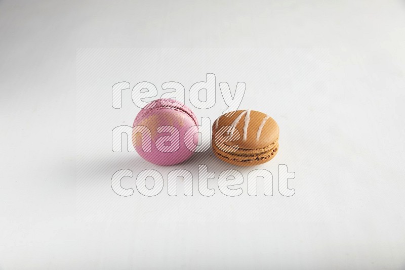 45º Shot of of two assorted Brown Irish Cream, and Purple Strawberry macarons on white background