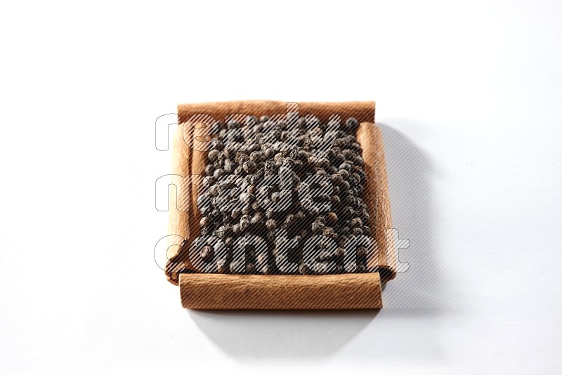 A single square of cinnamon sticks full of black pepper on white flooring