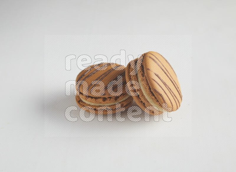 45º Shot of two light brown  Almond Cream macarons on white background