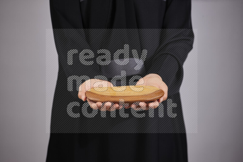A woman in black abaya holding different wooden essentials in different positions