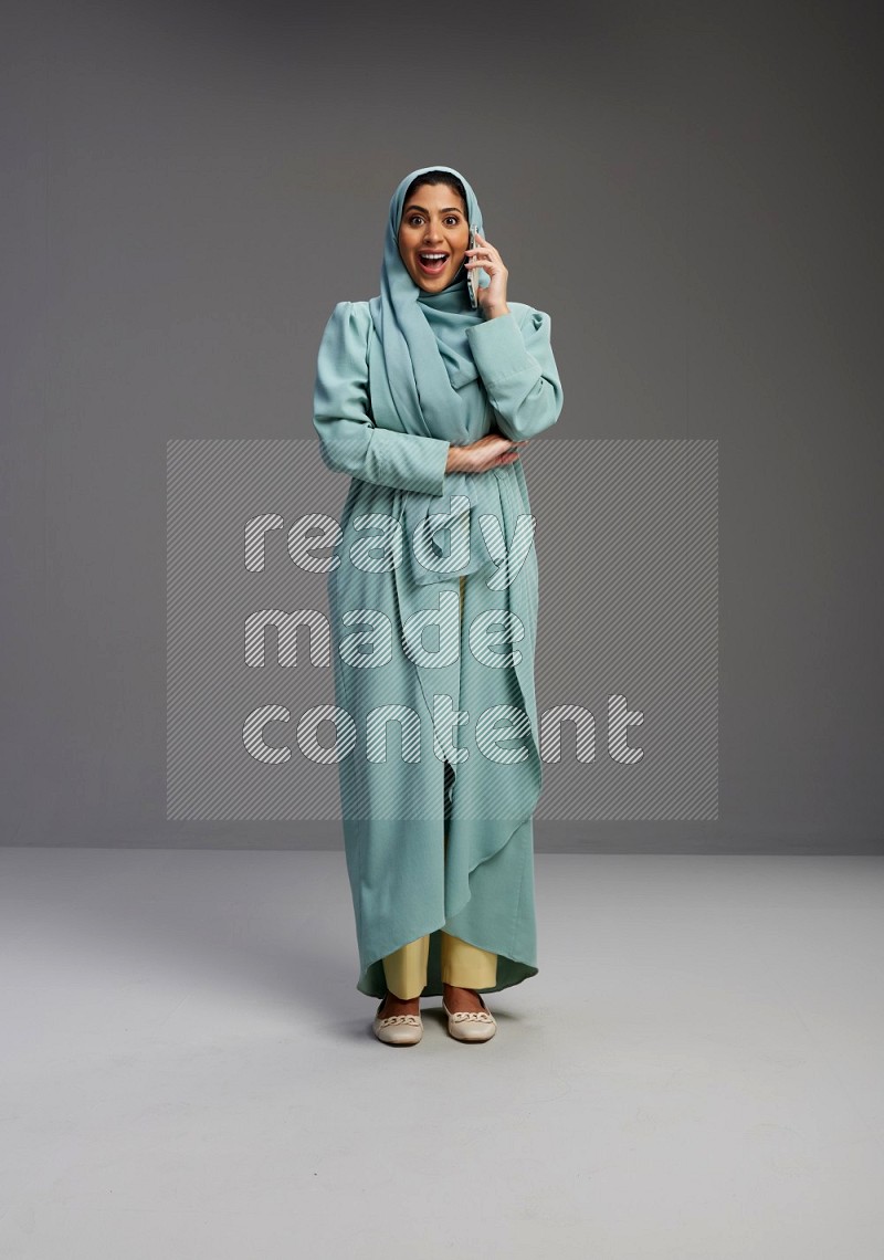 Saudi Woman wearing Abaya standing talking on phone on Gray background