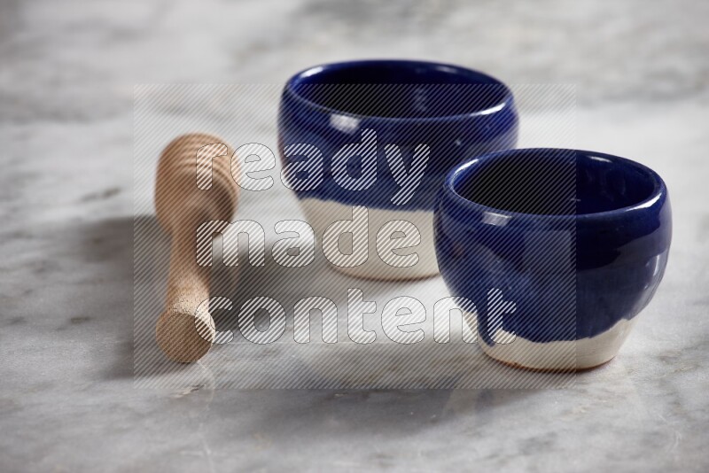 Multicolored pottery bowls with wooden honey dipper on the side on grey marble background