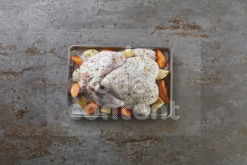 whole Raw chicken on a small oven trey direct on a rustic grey background