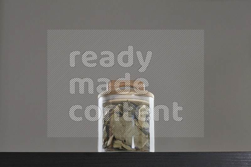 Bay laurel leaves in a glass jar on black background