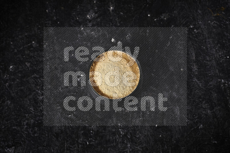 وعاء فخاري أسود ممتلئ ببودرة الزنجبيل علي خلفية سوداء