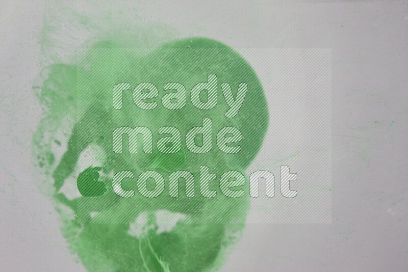 The image captures a dramatic splatter of green paint over a white backdrop