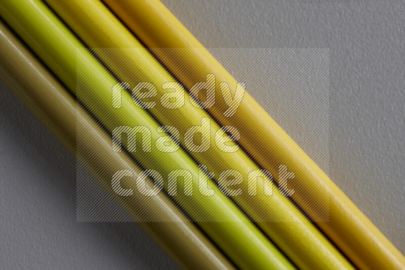 A collection of sharpened colored pencils arranged showcasing a gradient of yellow hues on grey background