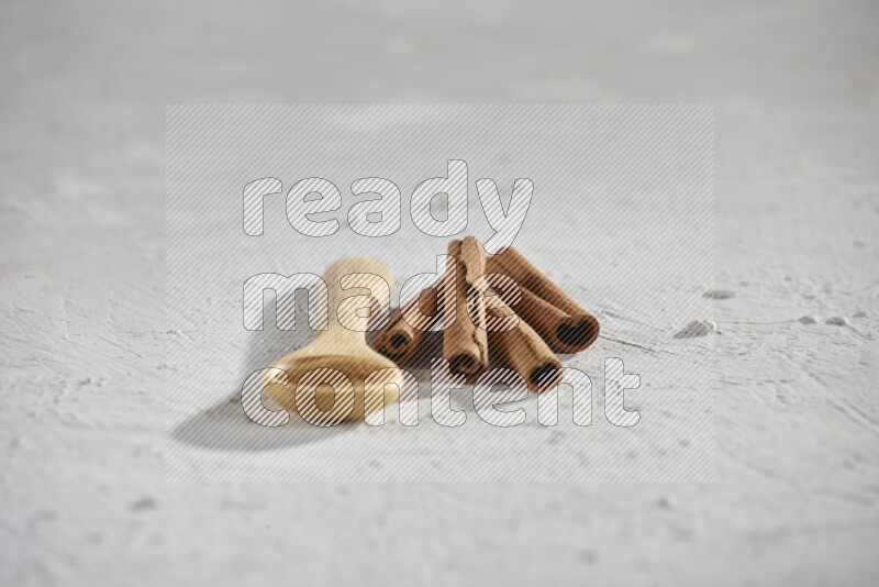 Cinnamon powder in a wooden spoon with cinnamon sticks on white background
