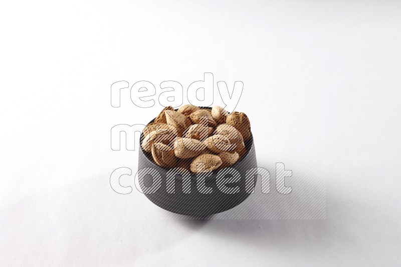 Almonds in a black pottery bowl on white background