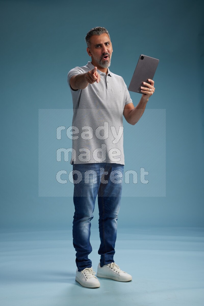 Man Standing working on tablet on blue background