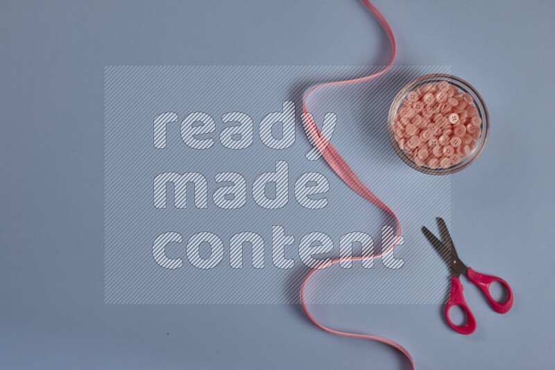 مجموعة من أدوات الخياطة والتفصيل زهرية اللون على خلفية زرقاء