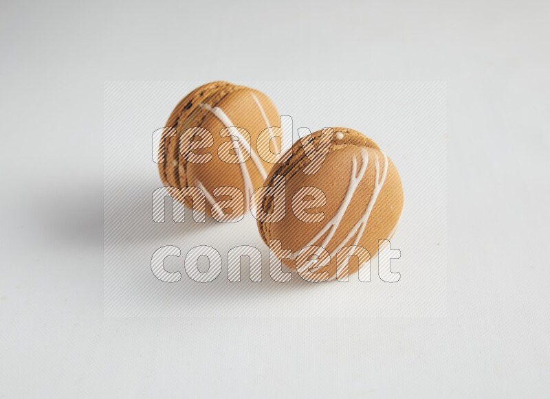 45º Shot of two Brown Irish Cream macarons on white background