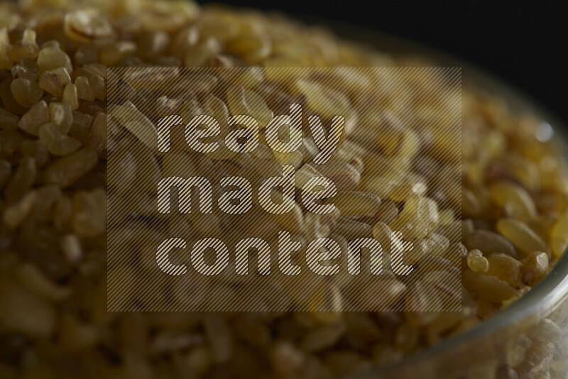 برغل خشن في وعاء زجاجي على خلفية سوداء