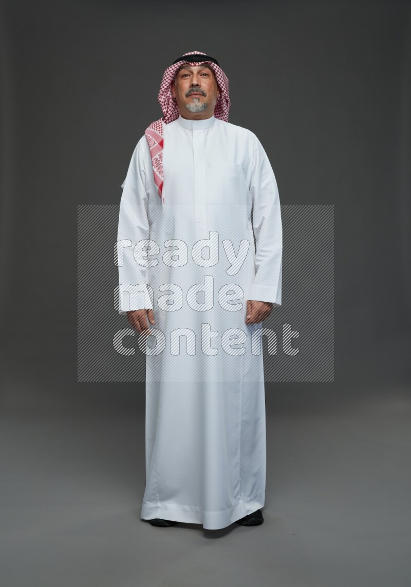 Saudi man with shomag Standing Interacting with the camera on gray background