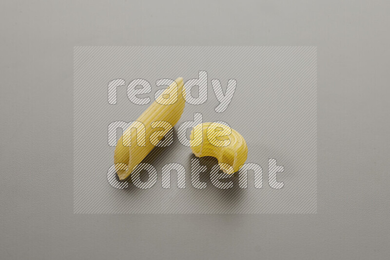 Penne pasta with other types of pasta on grey background