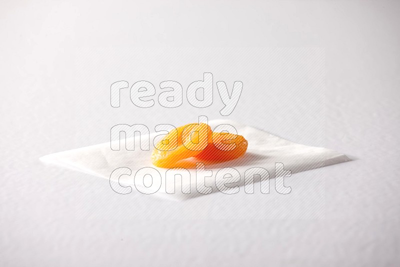 Two dried apricots on a piece of paper on a white background in different angles