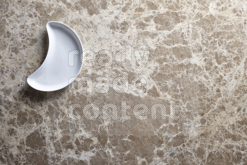 A pottery crescent plate on beige marble background