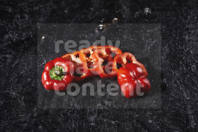 Red bell pepper slices on black background
