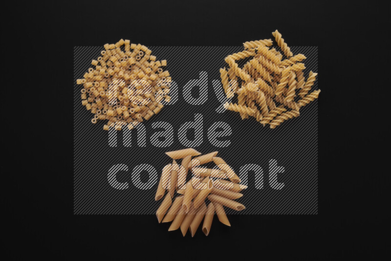 Different pasta types in bunches on black background
