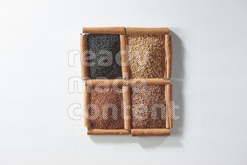 4 مربعات من أعواد القرفة ممتلئة بحبة البركة وبذور الخردل وبذور الكتان وحب الرشاد على أرضية بيضاء