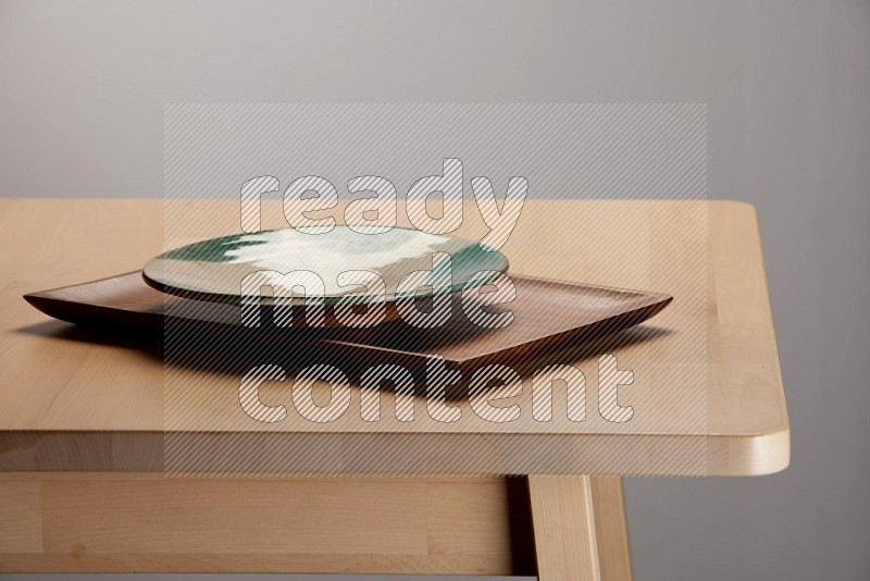 multicolored plate on a rectangular wooden tray on the edge of wooden table