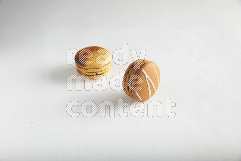 45º Shot of of two assorted Brown Irish Cream, and Yellow Crème Brulée macarons on white background