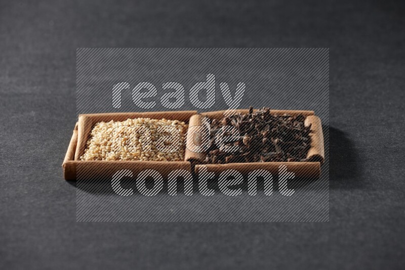 2 squares of cinnamon sticks full of sesame and cloves on black flooring