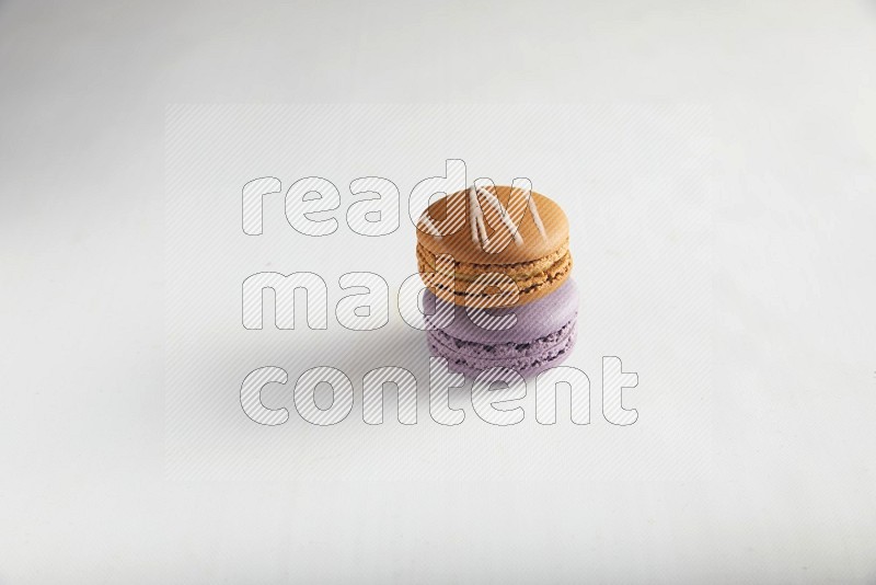 45º Shot of of two assorted Brown Irish Cream, and Purple Blueberry macarons on white background