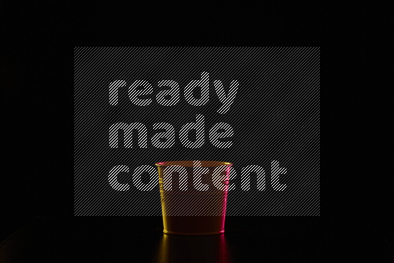 A plant pot with colored rim light against black background