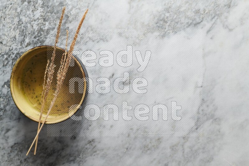 Wheat stalks on multicolored pottery oven plate on grey marble background