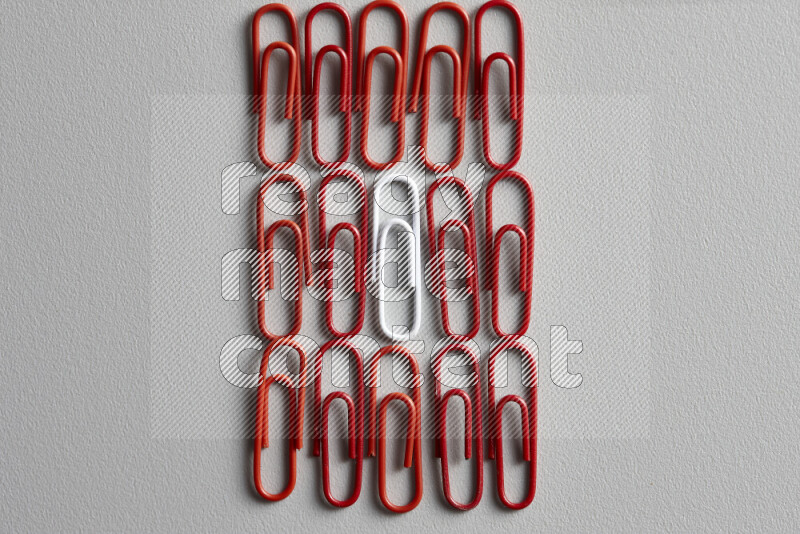 A white paperclip surrounded by bunch of red paperclips on grey background