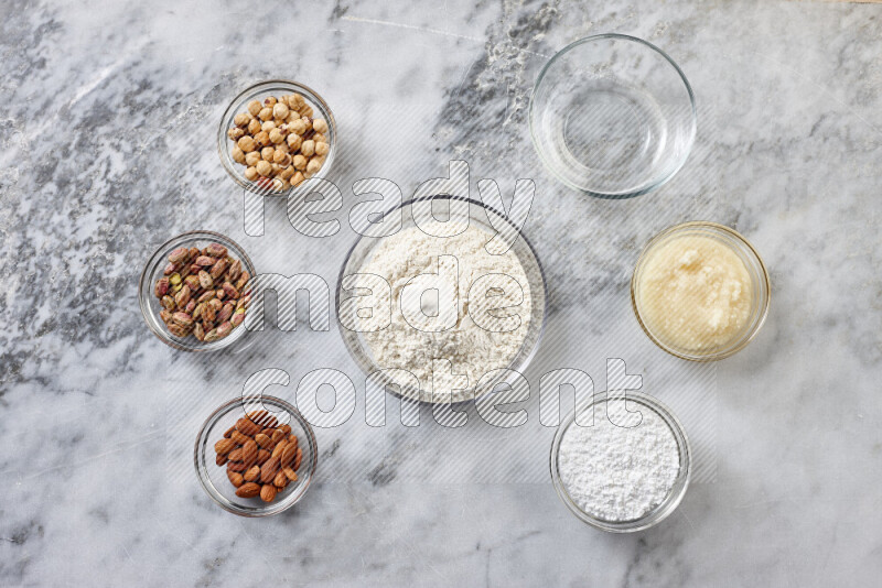 Ghoriba step by step with its ingredient, flour, powdered sugar, ghee and nuts on grey marble background