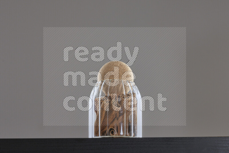 Cinnamon sticks in a glass jar on black background
