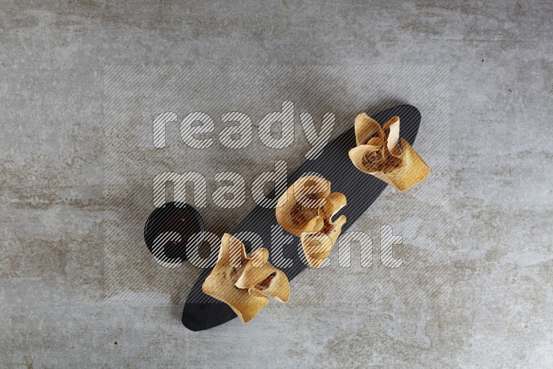 wonton cups with soy sauce ramkin on oval slate on grey textured counter top