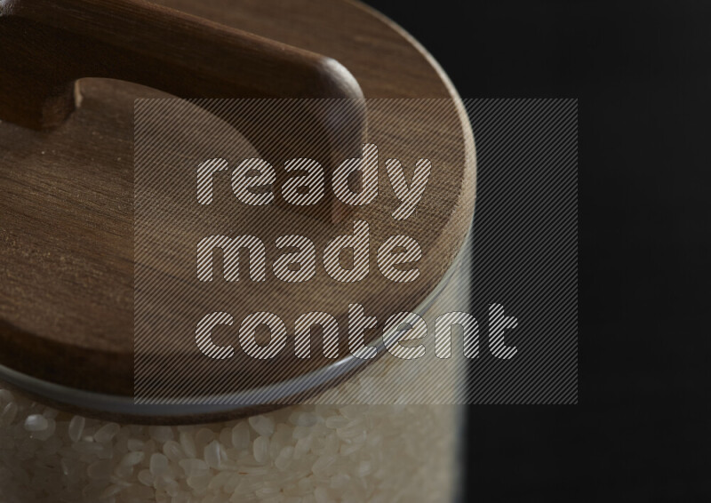 White rice in a glass jar on black background