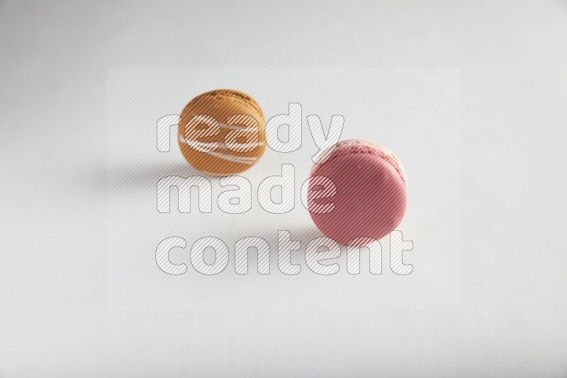 45º Shot of of two assorted Brown Irish Cream, and Pink Litchi Raspberry macarons on white background