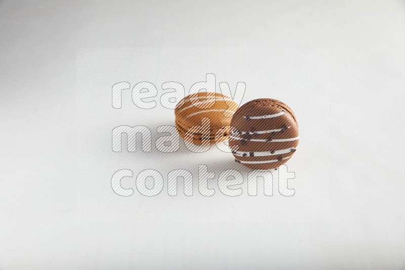 45º Shot of of two assorted Brown Irish Cream, and Brown white Chocolate Caramel macarons on white background