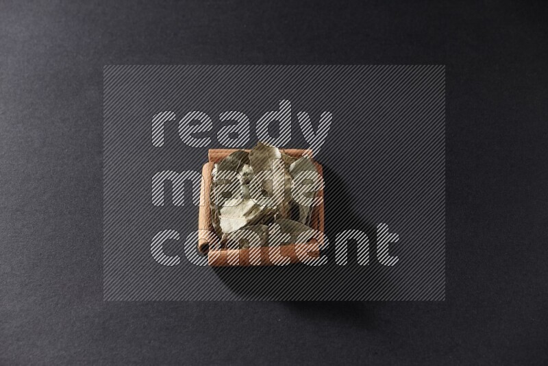 A single square of cinnamon sticks full of laurel bay on black flooring