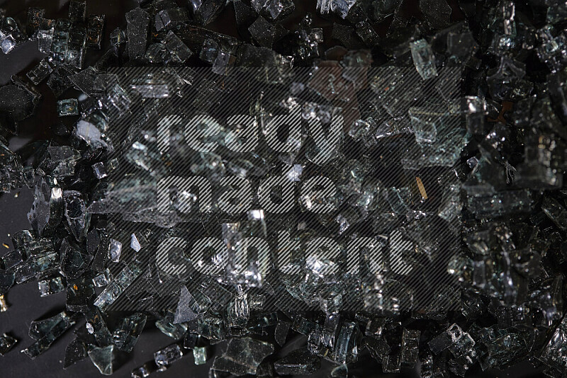 Transparent black fragments of glass scattered on a black background