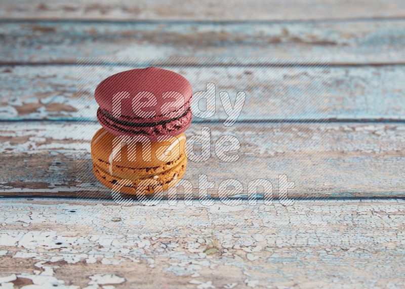 45º Shot of of two assorted Brown Irish Cream, and Red Cherry macarons  on light blue background