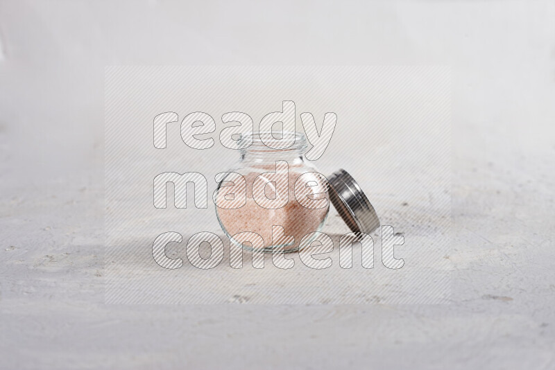 A glass jar full of fine himalayan salt on white background