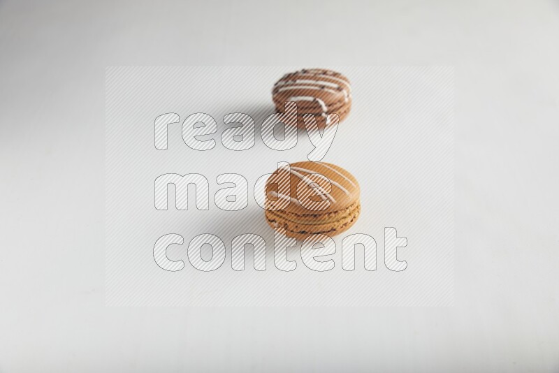 45º Shot of of two assorted Brown Irish Cream, and Brown white Chocolate Caramel macarons on white background