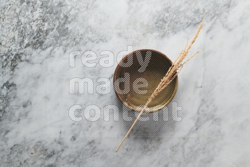 Wheat stalks on multicolored pottery oven plate on grey marble background