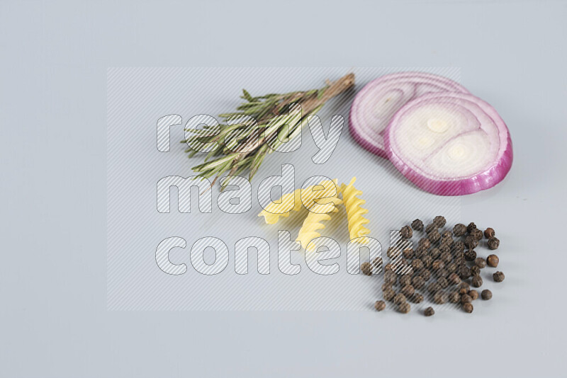 Raw pasta with different ingredients such as cherry tomatoes, garlic, onions, red chilis, black pepper, white pepper, bay laurel leaves, rosemary, cardamom and mushrooms on light blue background