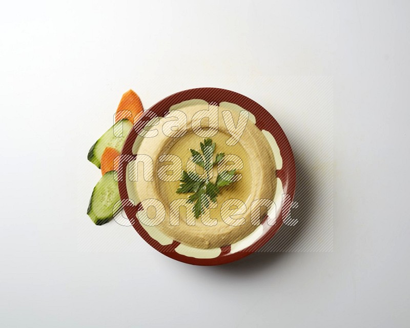 Hummus in a traditional plate garnished with parsley on a white background