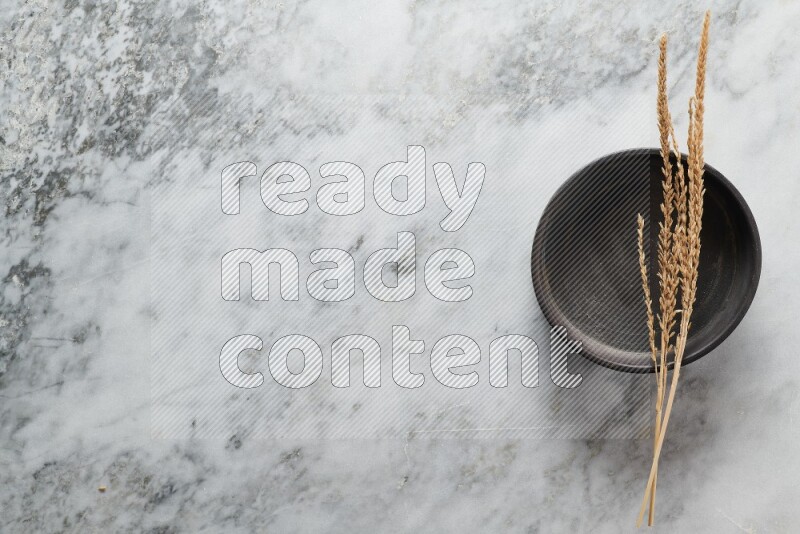 Wheat stalks on black pottery oven plate on grey marble background