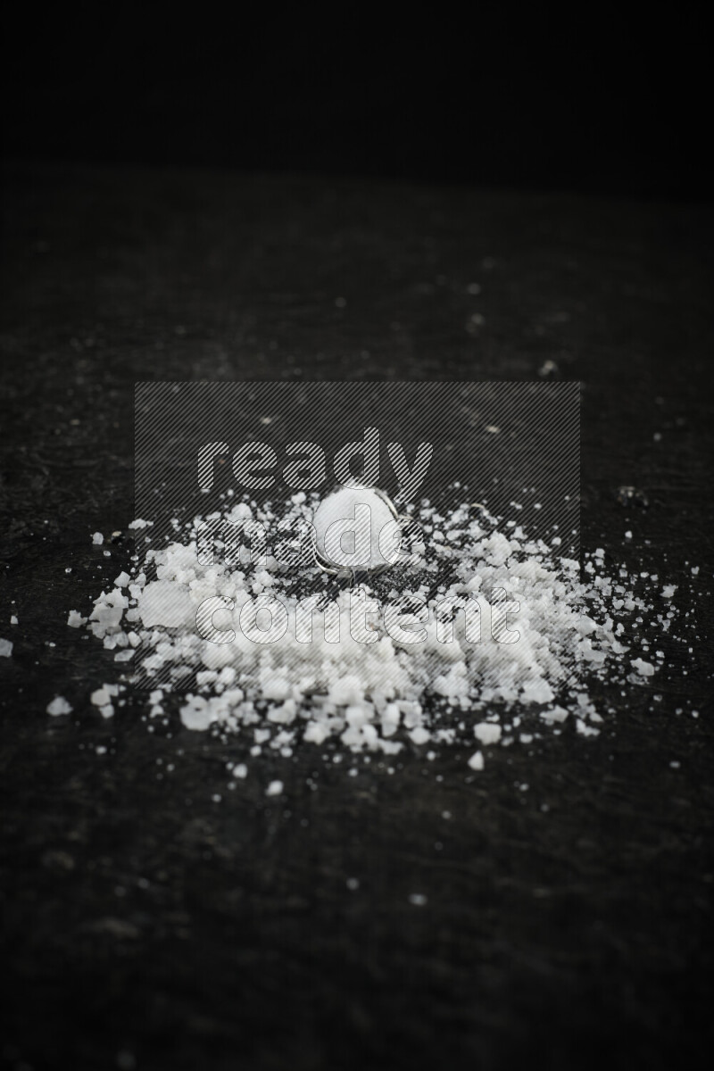 ملعقتان معدنيتان ممتلئتان بالملح الأبيض على خلفية سوداء