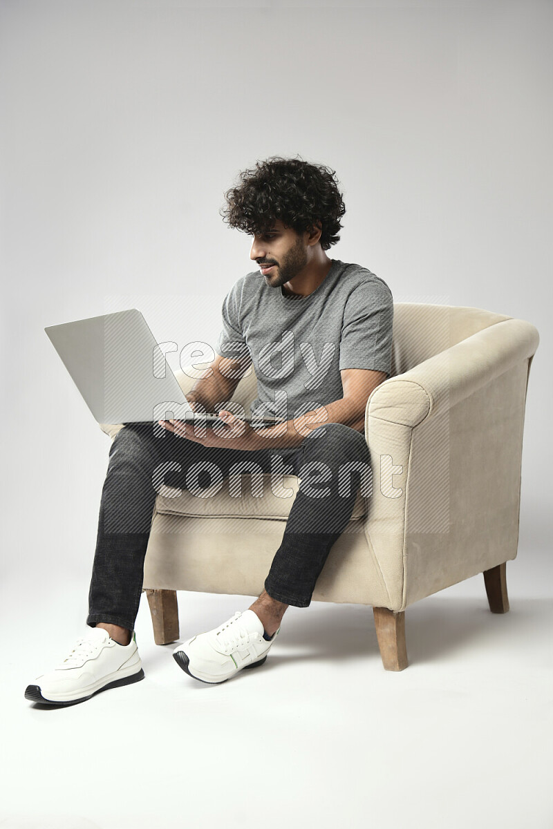 A man wearing casual sitting on a chair working on a laptop on white background